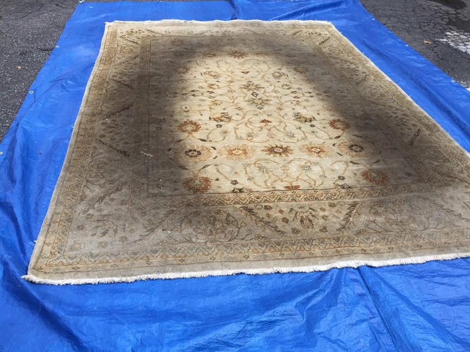 Soiled cream rug laid out flat for assessment