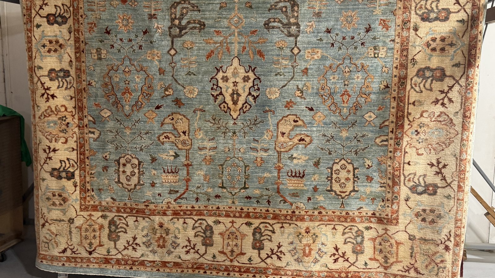 Pale blue and cream hand-knotted rug hanging over a drying rack