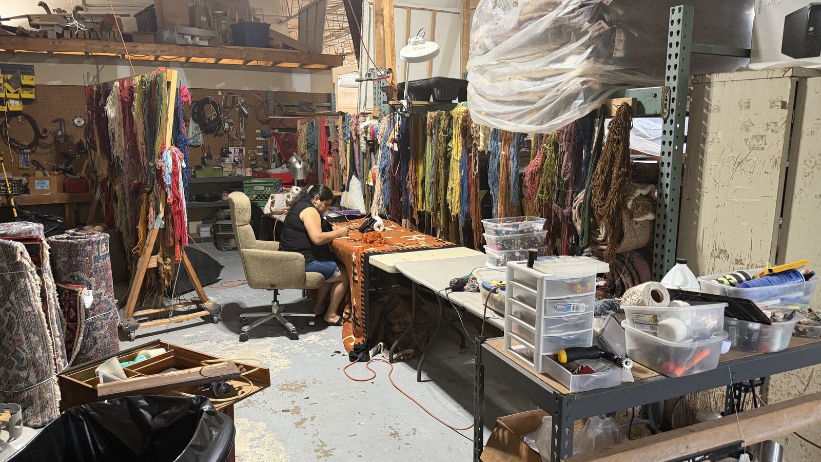 Rug repair bench with hand-dyed wool skeins sorted by colour